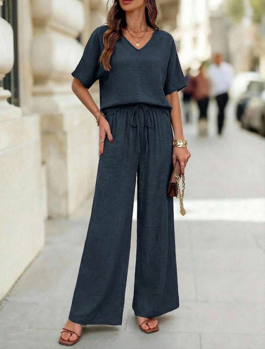 Model wearing a dark teal V-neck short sleeve top and wide-leg pants set with drawstring waist